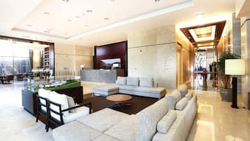 A modern hotel lobby with a large sectional sofa, a coffee table, and a reception desk.