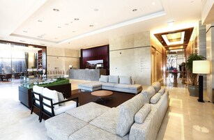 A modern hotel lobby with a large sectional sofa, a coffee table, and a reception desk.