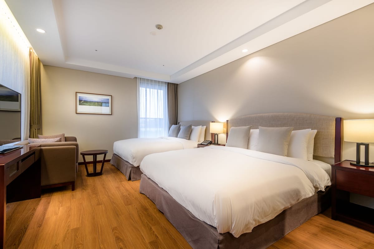 Een hotelkamer met twee bedden, een bureau, een stoel en een tafeltje.