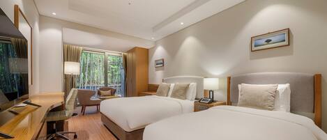 A hotel room with two beds, a desk, a chair, a TV, and a window with a view of bamboo outside.