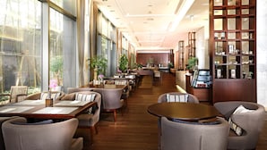 Un hall d’hôtel spacieux, doté d’un long comptoir d’accueil, de plusieurs espaces salon et d’un bar à café.