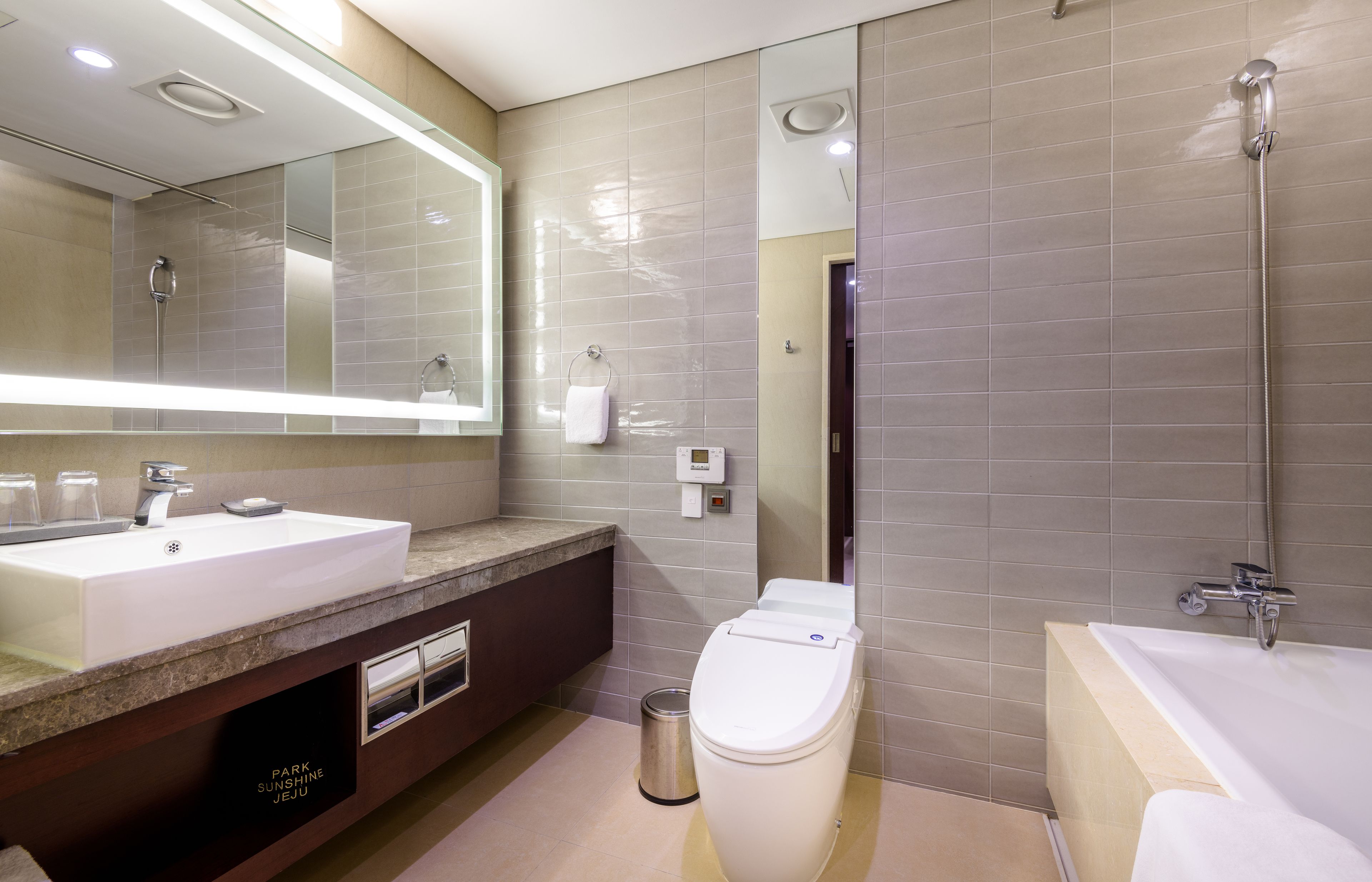 A modern bathroom with a large sink, mirror, toilet, and shower area.