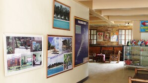 Een hotel lobby met een houten receptiebalie, foto's in lijsten aan de muur en een glazen vitrine met souvenirs.