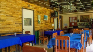 Een restaurant met houten wanden, blauwe tafelkleden en houten stoelen.
