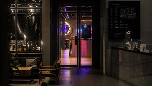 A modern interior with a reception desk, seating area, and a directory sign. - THA City Loft by TH District (Bangkok)