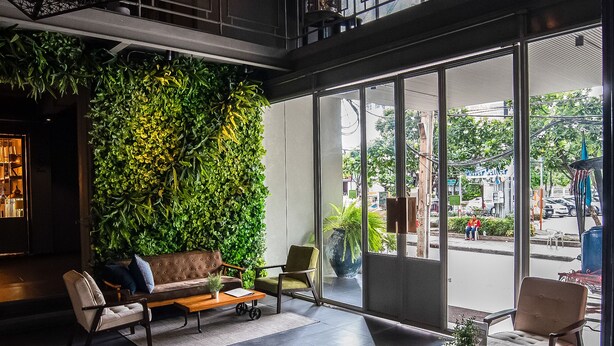 A modern interior with a green wall, seating area, and large windows. - THA City Loft by TH District (Bangkok)