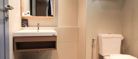 Un baño moderno con lavamanos, espejo, inodoro y ducha.