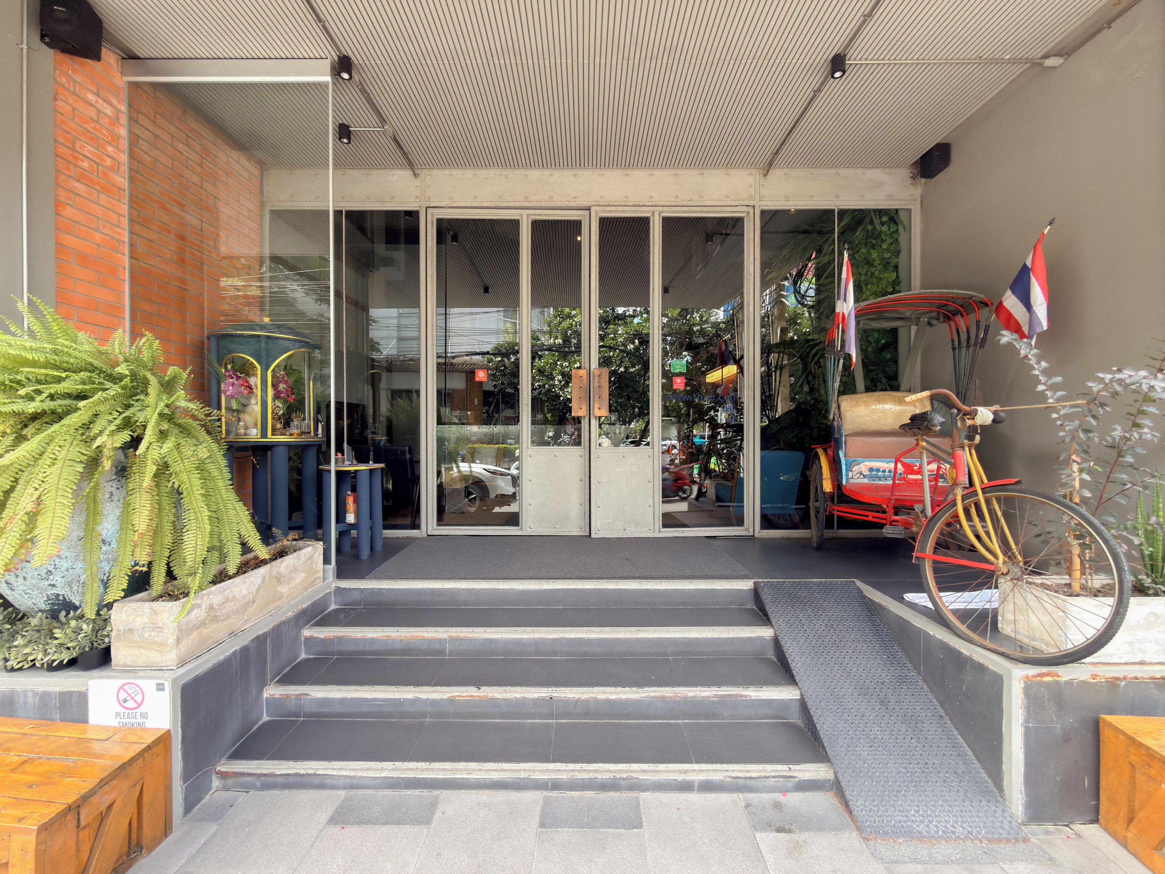 A building entrance with a glass door, steps leading up to it, and a bicycle parked outside.