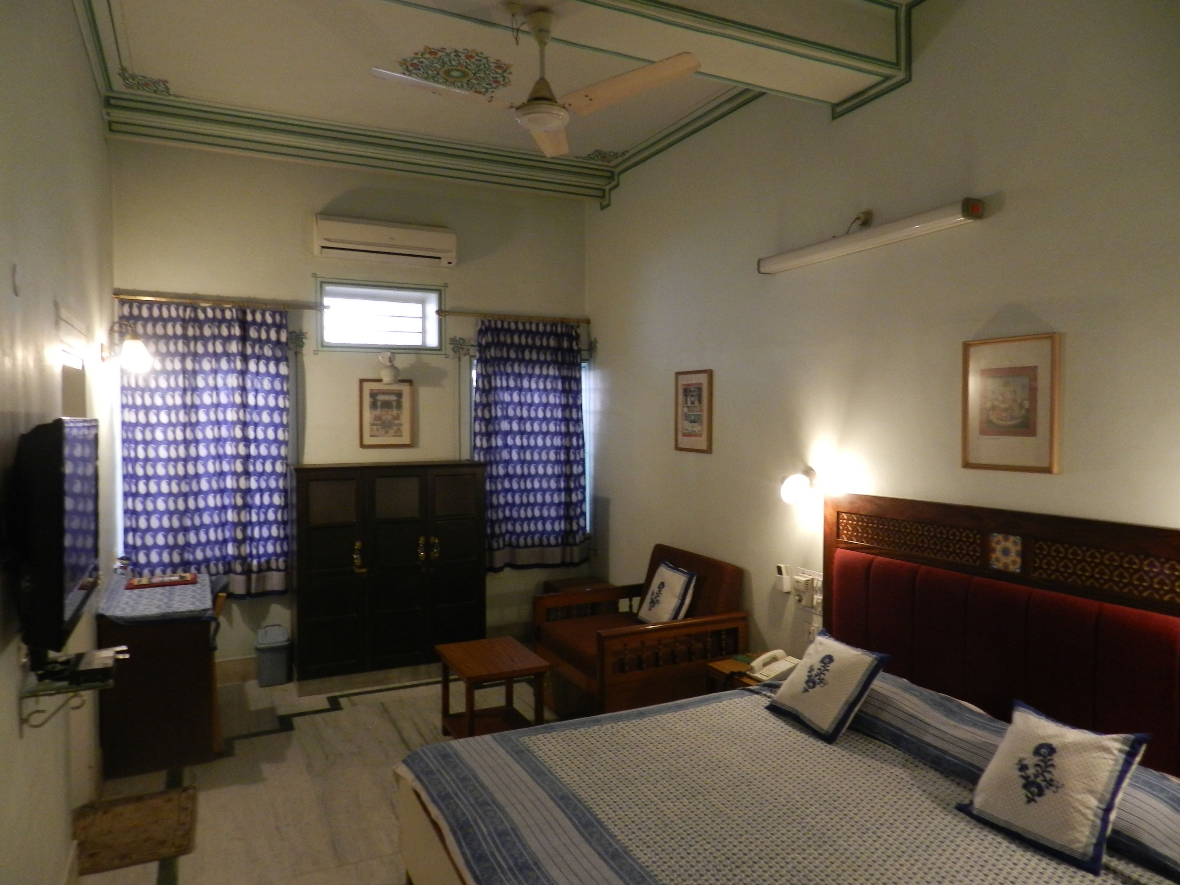 Un dormitorio con cama, escritorio, armario y ventilador de techo.
