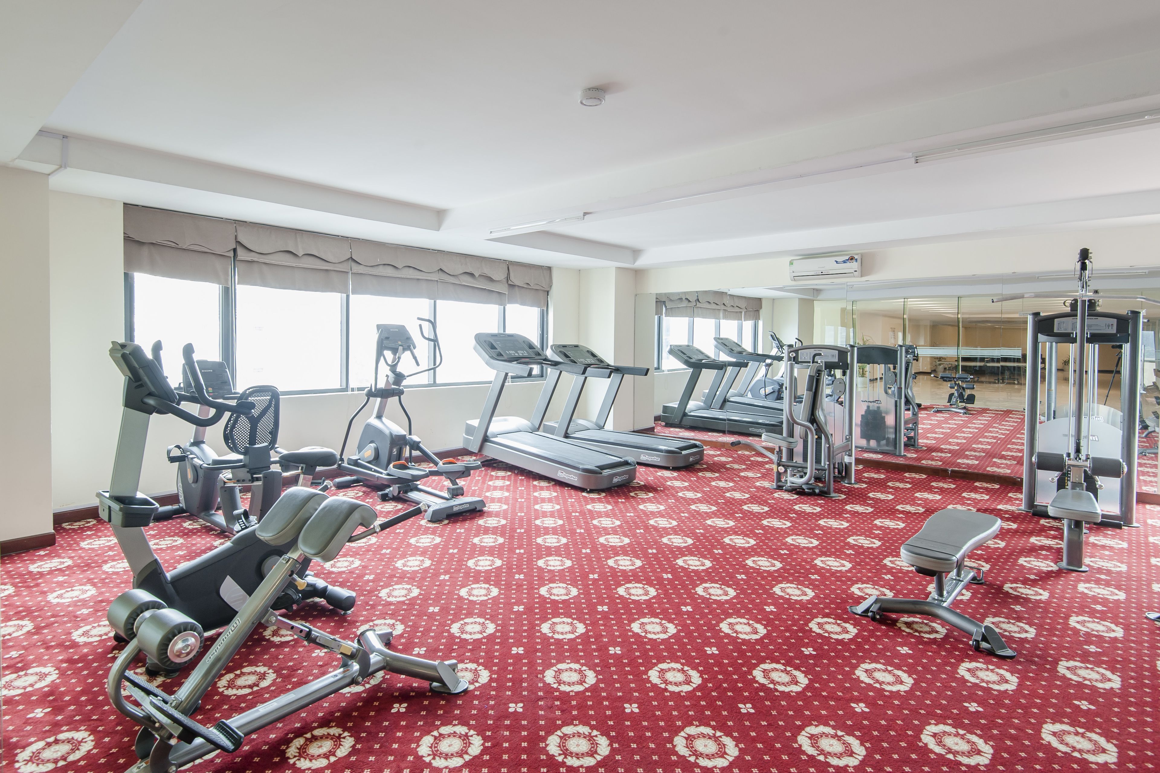 Een fitnessruimte met loopbanden, elliptische trainers en gewichten.