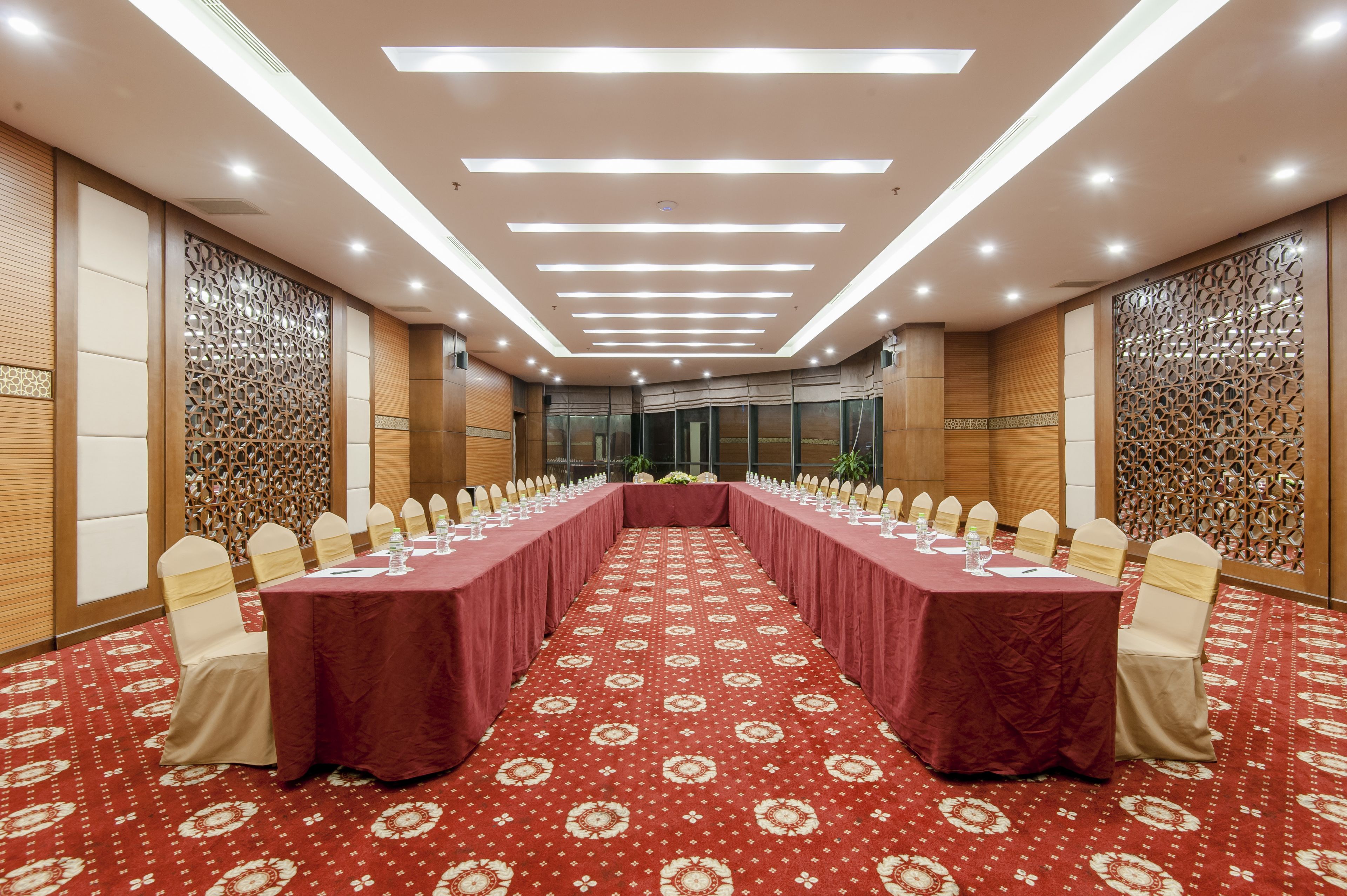 A conference room with a long table, white chairs, and a red carpet.