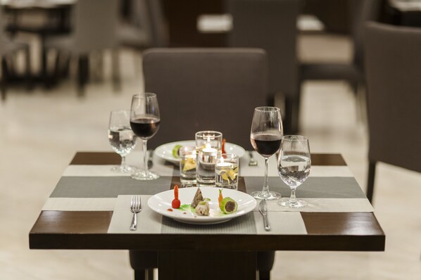 Una mesa de comedor dispuesta con platos, vasos y velas, que sugiere un restaurante.