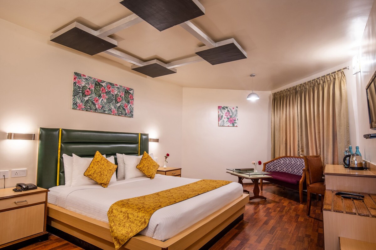 A hotel room with a bed, a desk, a chair, and a small table.