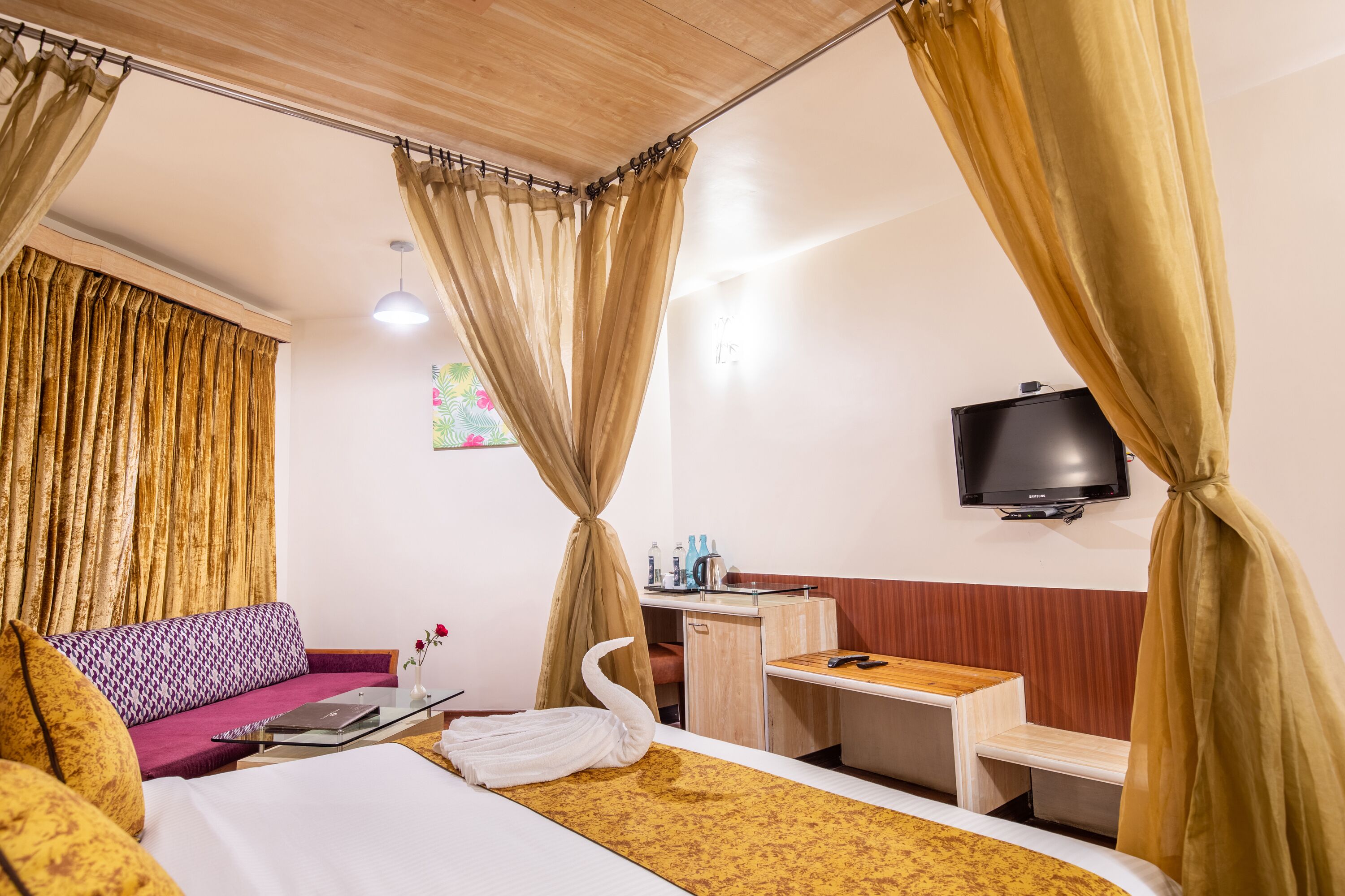 A hotel room with a bed, a desk, a television, and a sofa.