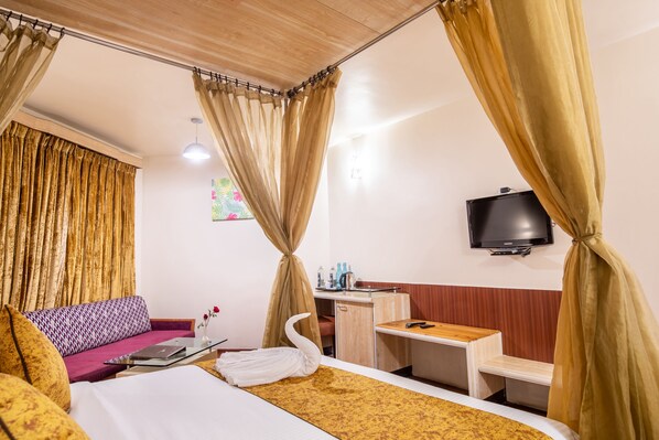 A hotel room with a bed, a desk, a television, and a sofa. - Poppys Pleasant Stay (Kodaikanal)