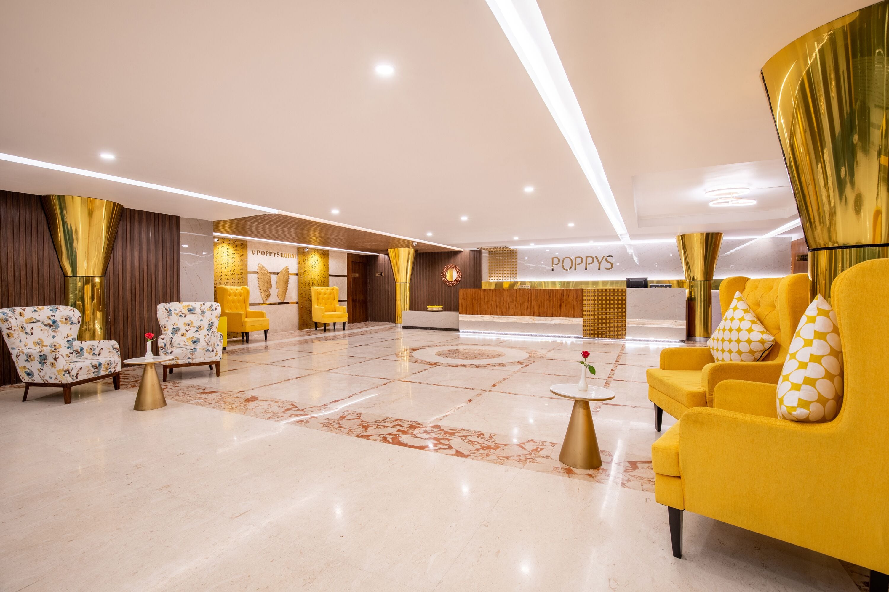 A modern lobby with a reception desk, yellow and white patterned armchairs, and a marble floor.