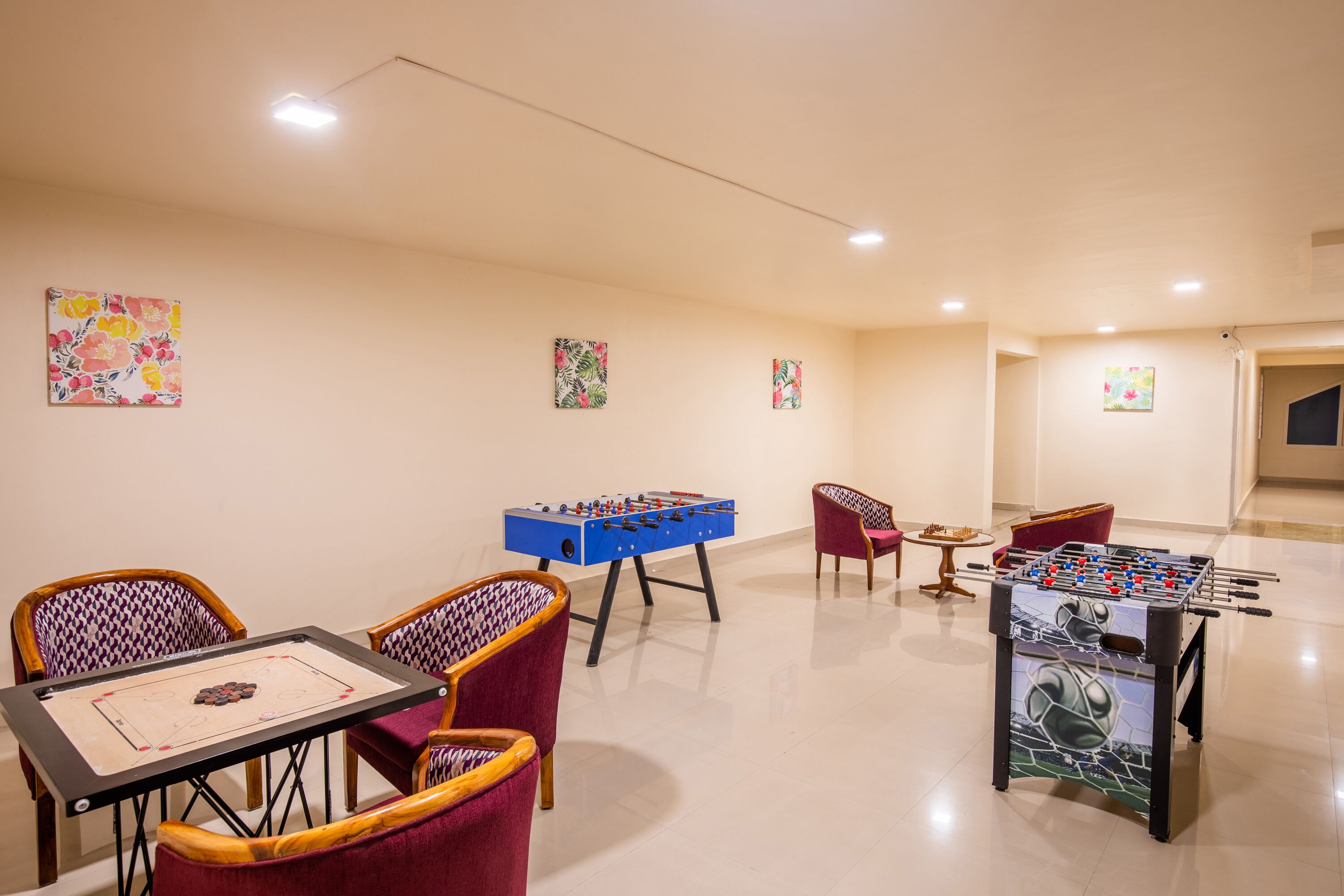 Une pièce équipée de deux tables de baby-foot, d’une table de ping-pong et de plusieurs chaises.