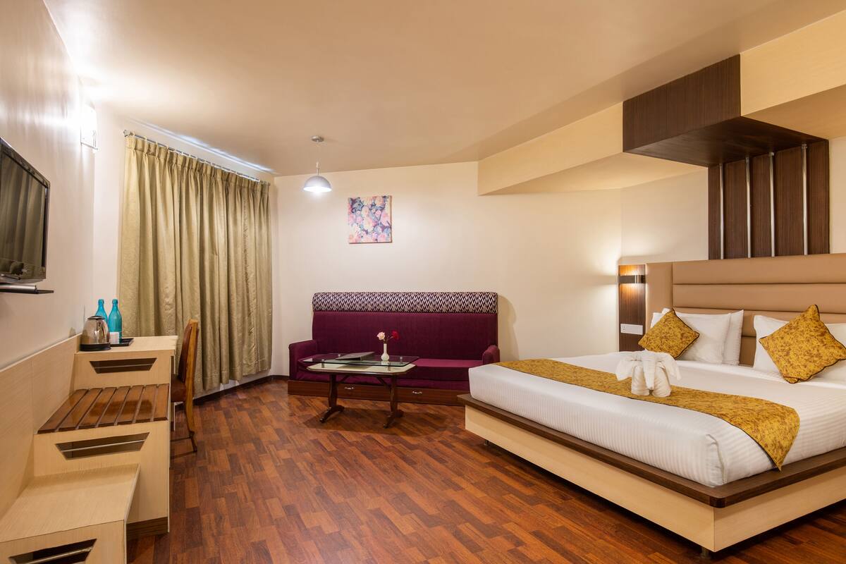 Ein Hotelzimmer mit Bett, Sofa, Schreibtisch und Stuhl.
