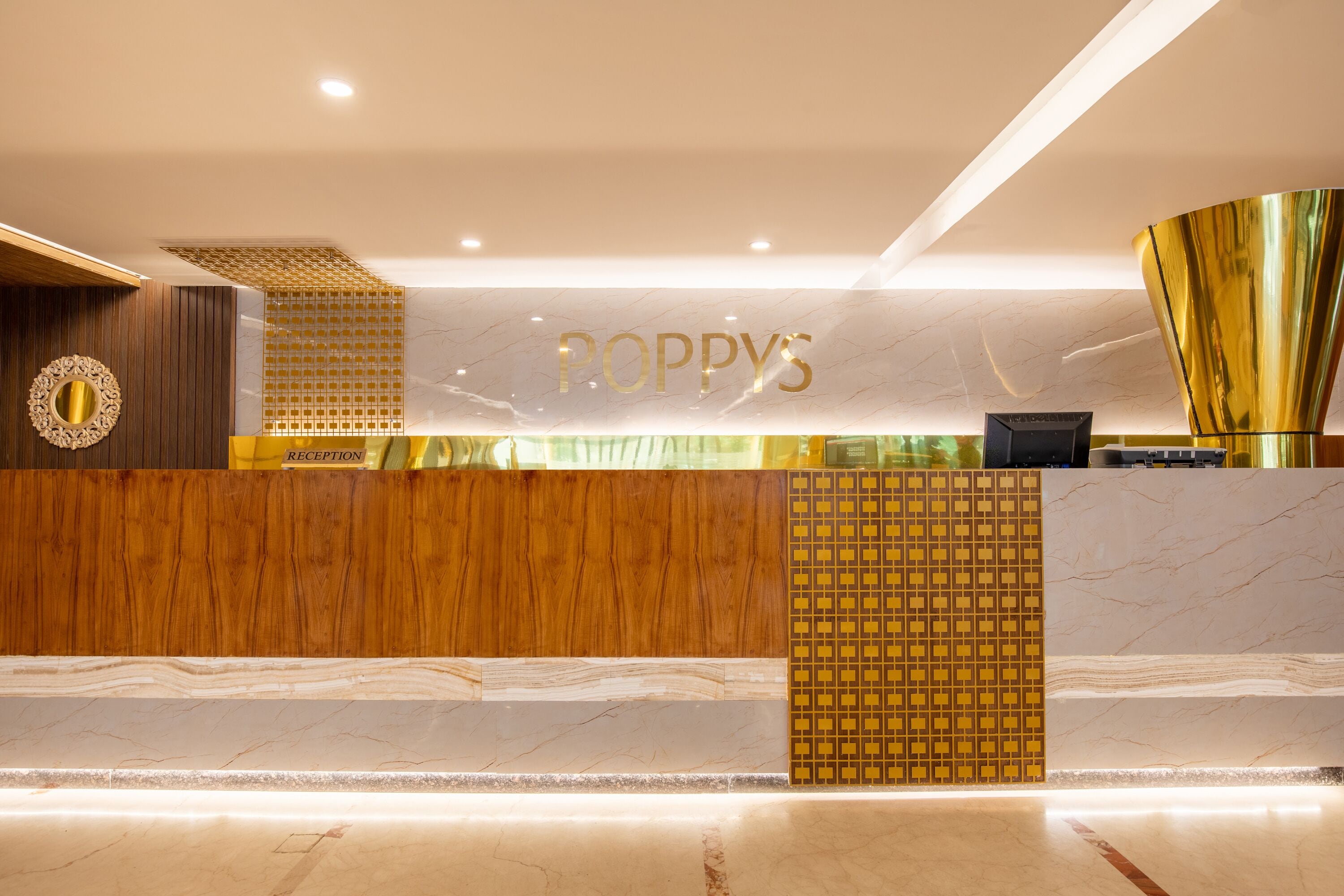A reception area with a marble reception desk, a gold-colored reception desk, and a gold-colored wall.