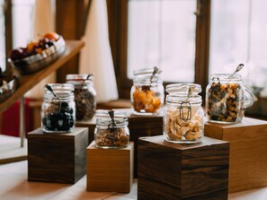 A breakfast buffet with various food items in glass jars on wooden stands. - Hotel Schützen Steffisburg (Steffisburg)