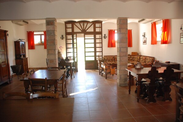 A spacious dining area with high ceilings and stone pillars, featuring a large wooden table and chairs. - Agriturismo Le Volte (Gubbio)