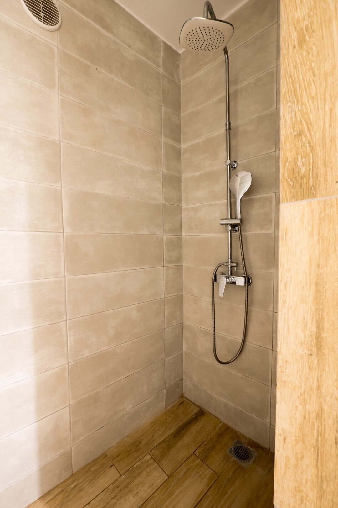Une douche équipée d’un pommeau de douche à main et d’un robinet fixé au mur.