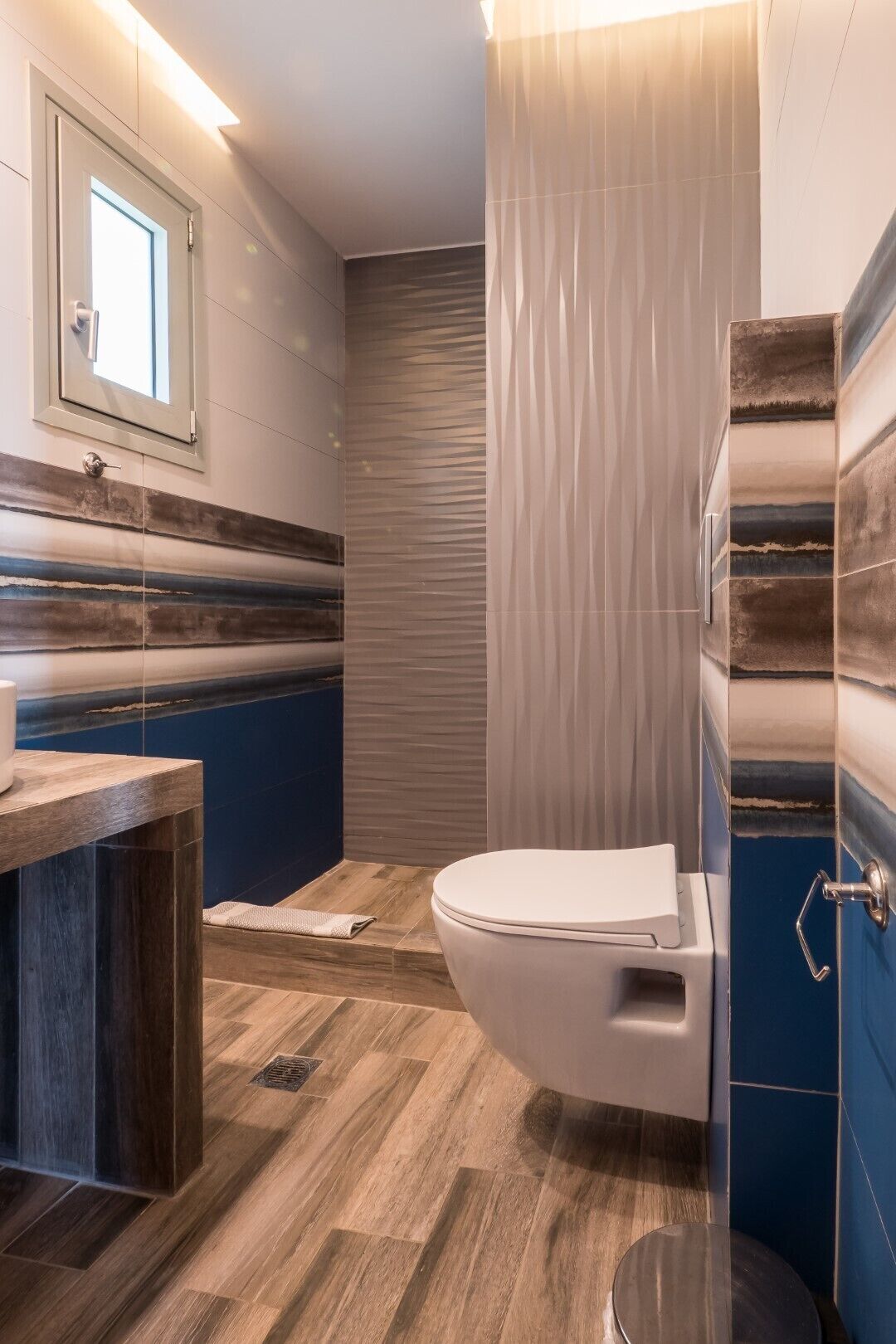 A modern bathroom with a wooden vanity, a toilet, and a shower area.