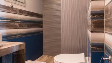 A modern bathroom with a wooden vanity, a toilet, and a shower area.
