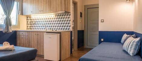A compact room with a kitchenette, a bed, and a seating area.