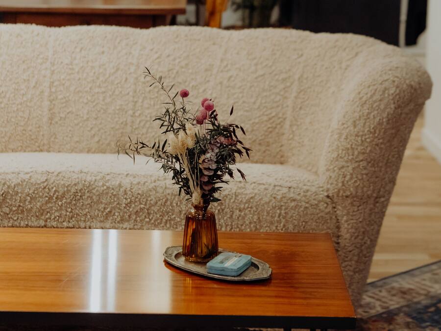 Una sala de estar con un sofá, una mesa de centro y un jarrón con flores.