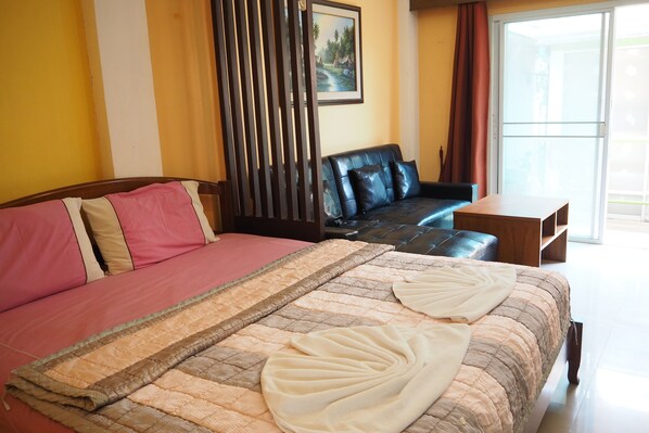 Quarto de hotel com cama, sofá, mesa de madeira e um quadro na parede.