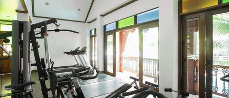 A gym with cardio machines, weight machines, and a large window with a view of the outdoors.