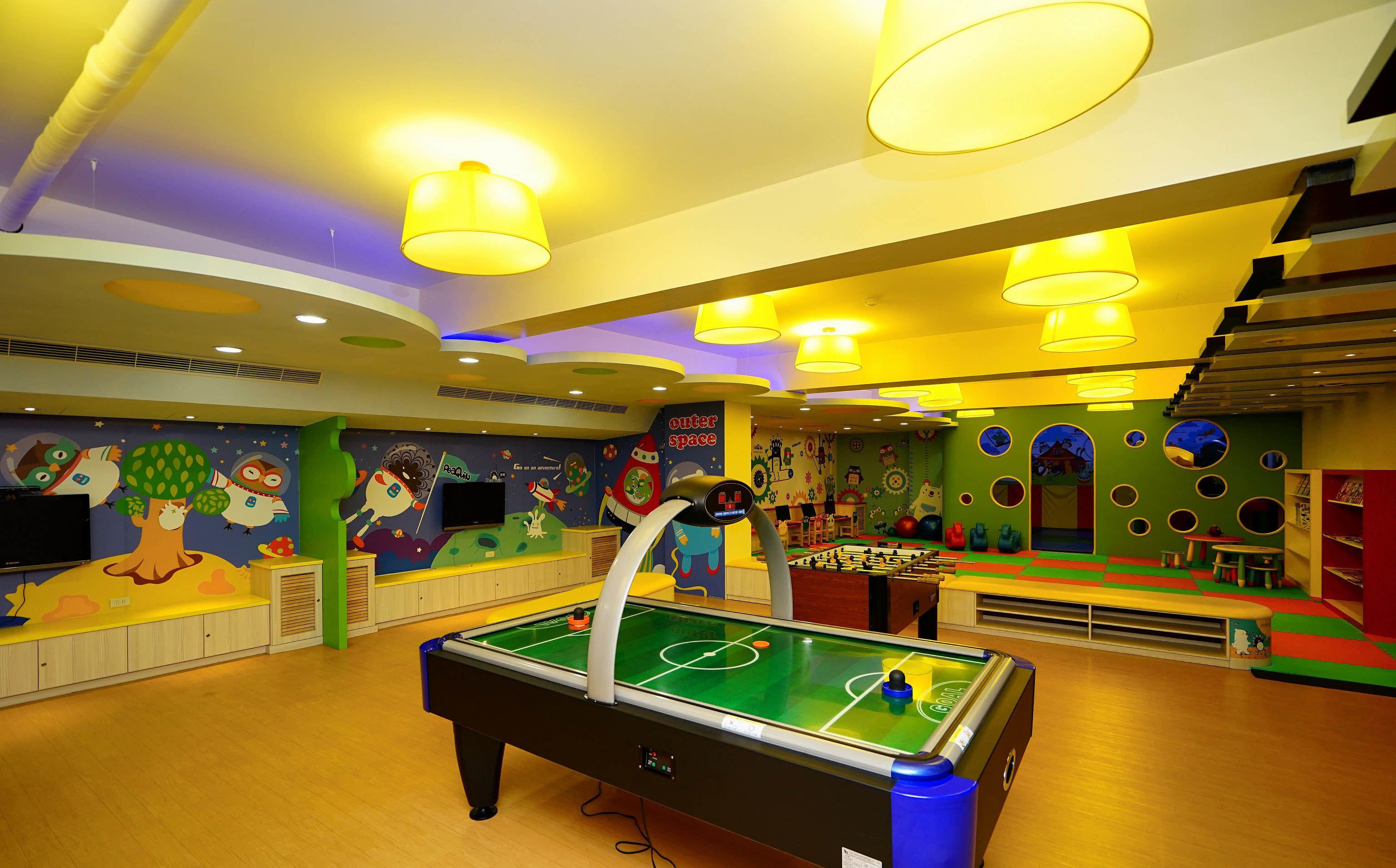 Un espace de jeux intérieur, bien éclairé, avec une table de billard, des peintures murales colorées et un panneau indiquant « espace ».