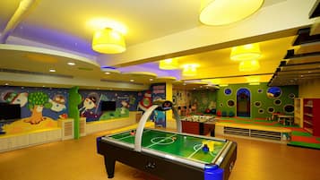 Un área de juegos interior muy iluminada con una mesa de billar, murales coloridos y un letrero que dice "outer space".