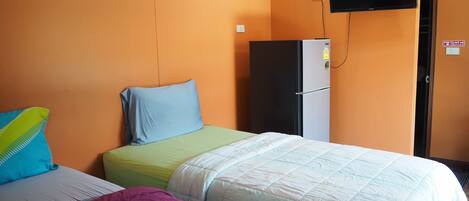 Una habitación con dos camas, un refrigerador, un televisor y una puerta con un letrero.