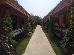 A pathway flanked by potted plants and a building with a tiled roof.