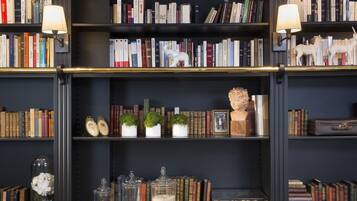 A bookshelf with books, decorative items, and two wall-mounted lamps.