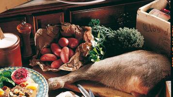 A rustic kitchen setting with a variety of food items, including a whole fish, apples, and a pie on the table.