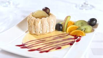Een dessertborden met een meringue, kiwi, sinaasappel en druiven.