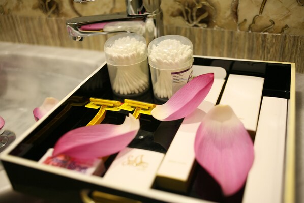 A bathroom vanity with a black countertop, a sink, and a mirror. There are two containers of cotton swabs and a bottle of hand soap. - Church Legend Hotel Hanoi (Hanoi)