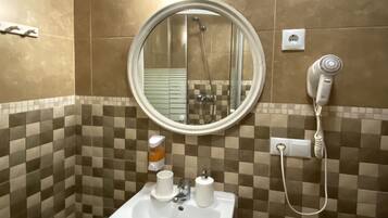 A bathroom with a sink, mirror, and a hairdryer on the wall.