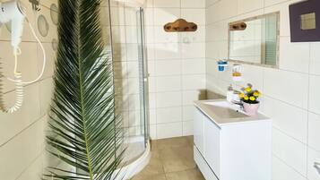 A bathroom with a shower, a sink, a mirror, and a toilet.