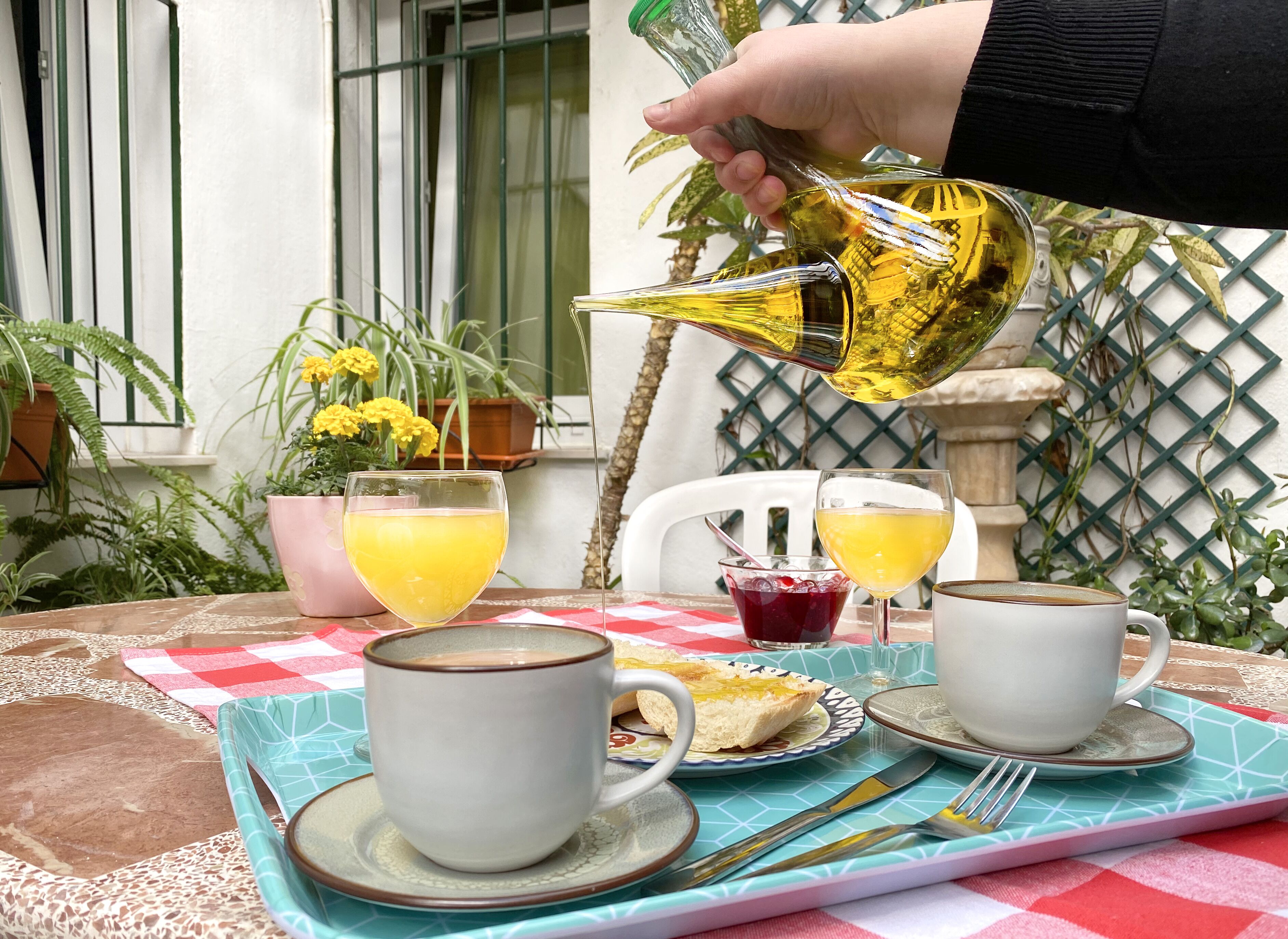 A table set with two white cups, a glass of orange juice, a glass of red juice, a plate with toast, and a fork.