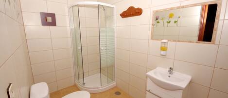 A bathroom with a toilet, a glass-enclosed shower, and a sink.