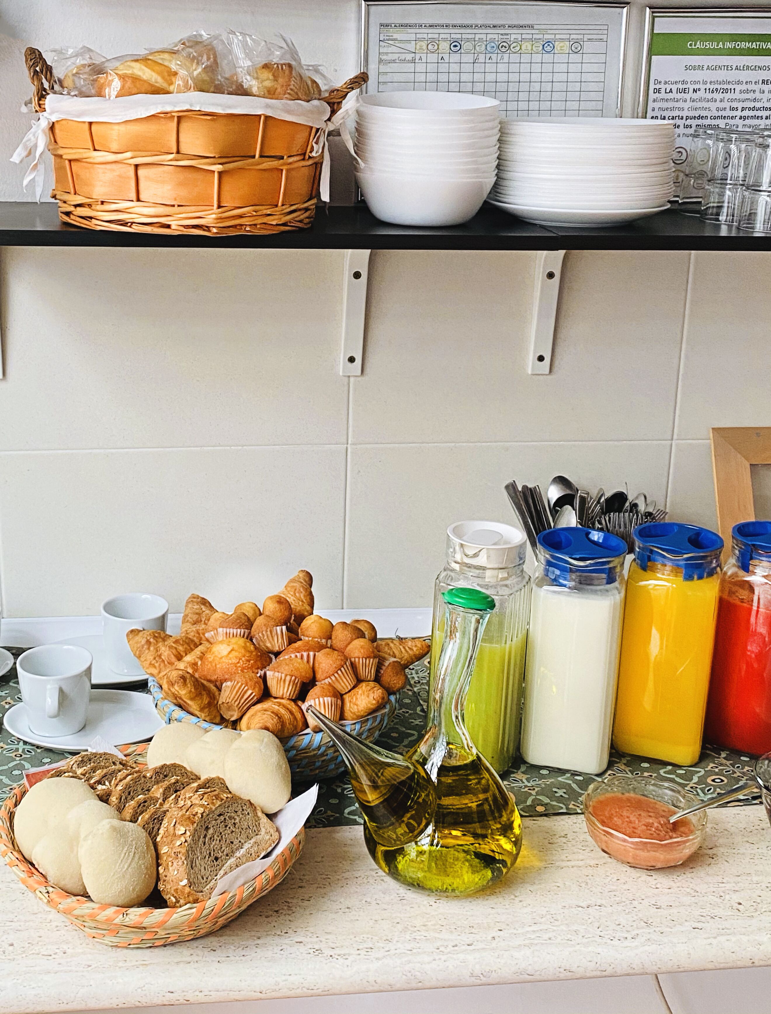 Una encimera de cocina con diversos alimentos, como pan, pasteles y salsas.