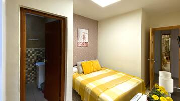Un dormitorio con cama, baño y una pequeña mesa con un florero.