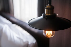 A close-up of a hanging light fixture with a visible bulb, a dark-colored ceiling, and a blurred background suggesting a room interior. - Khan Hotel (Kaohsiung)