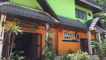 A building with a green and orange facade, a tiled roof, and a sign for 'Trekker Camp'.