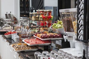 A buffet with various food items including fruits, sandwiches, and desserts.