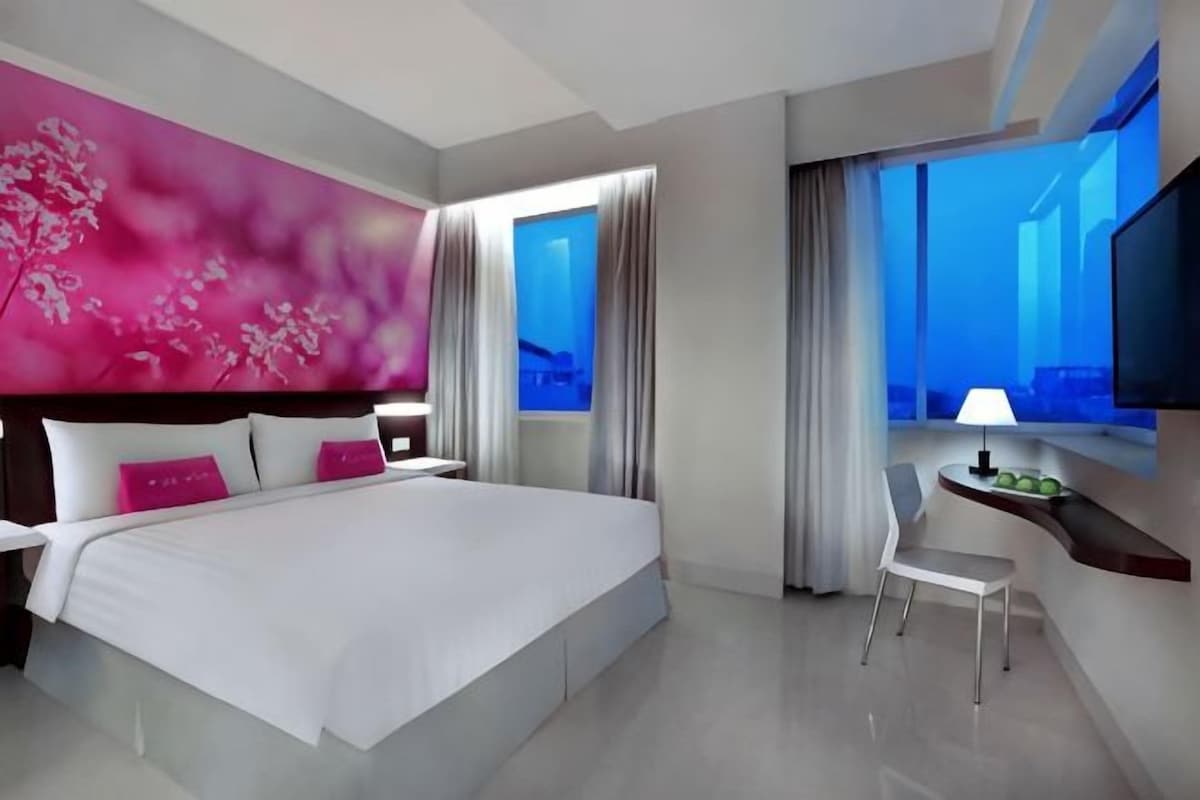 Habitació d'hotel moderna amb un llit gran, una taula de treball i una televisió.